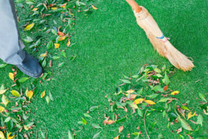 Man cleaning leaves from artificial grass